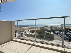 Ein Balkon mit freiem Blick auf den Strand und einen Parkplatz.