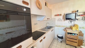 Eine kleine Küche mit Einbauofen, Spüle und einem kleinen Holzschrank.