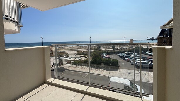 Ein Balkon mit freiem Blick auf einen Parkplatz und das Meer.