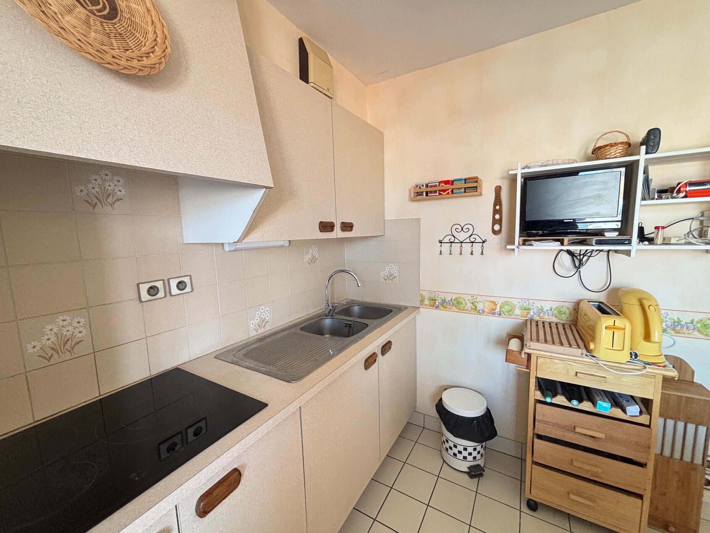 A kitchen with a stove, sink, and a small trash bin.