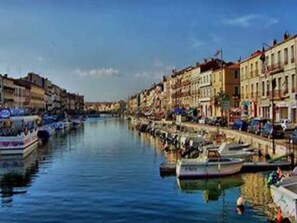 A canal lined with buildings, boats docked along the water's edge, and a clear sky. - Apartment with AC - Discover Sète (Sète)