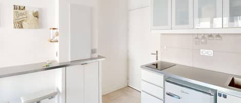 Una cocina moderna con gabinetes blancos, lavavajillas integrado y encimera de acero inoxidable.