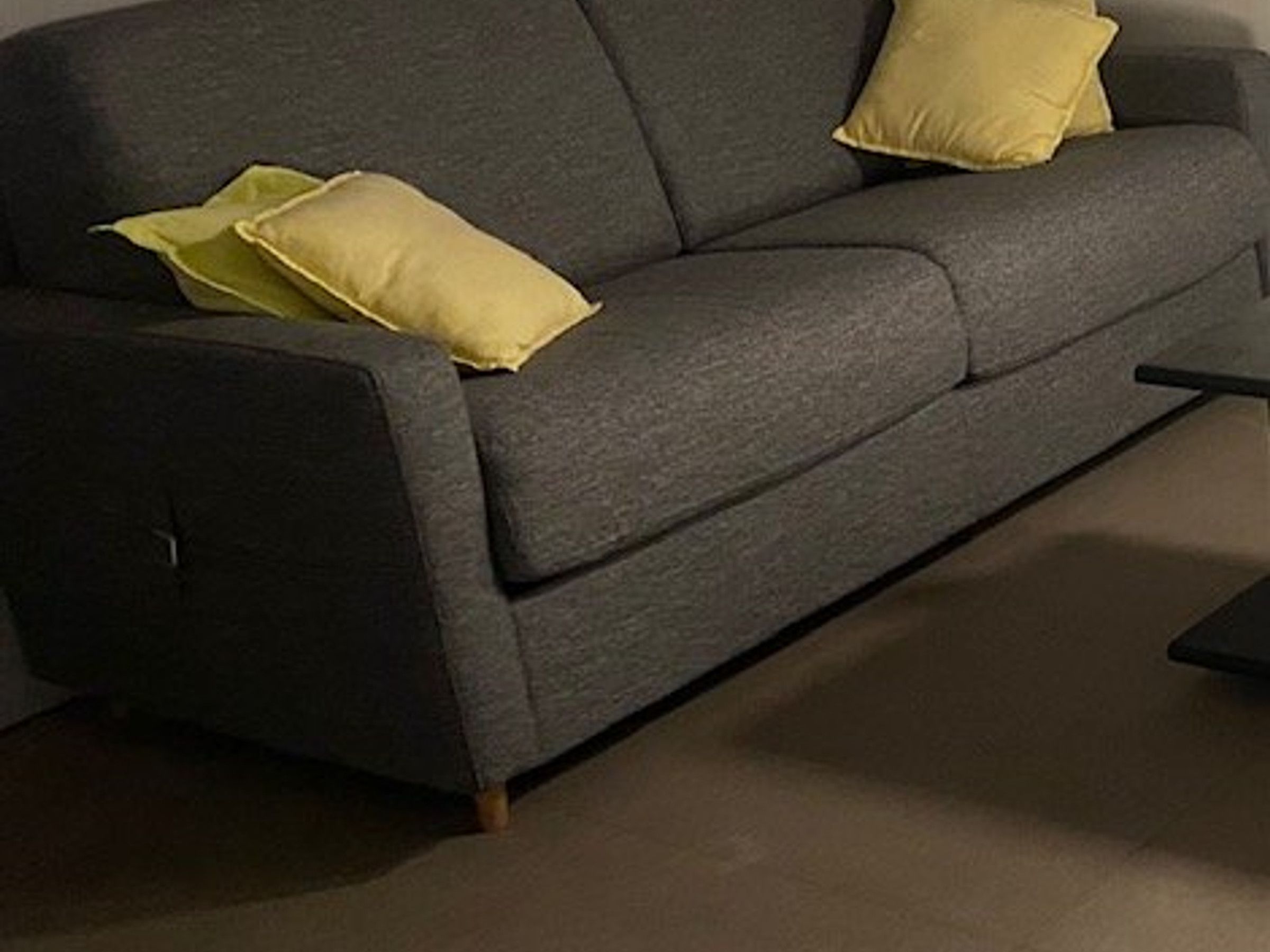 Un canapé de couleur sombre agrémenté de deux coussins jaunes.