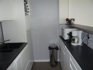 A compact kitchenette with a microwave, coffee maker, and a trash bin. - Apartment with AC and sea view - 4/5 guests (Port Camargue)