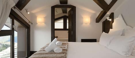 A bedroom with a large bed, a window, and a view of the mountains.