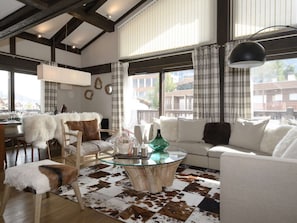 A modern living room with a glass coffee table, white sofas, and a cowhide rug. - Duplex apartment in the center - 8 guests (Courchevel 1650)