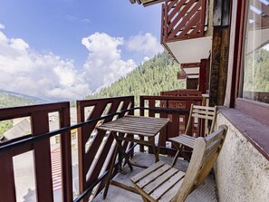 Eine Holzdachterrasse mit Tisch und Stühlen, mit Blick auf ein bewaldetes Gebiet.
