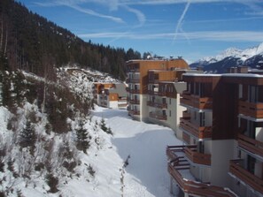 A row of modern multi-story buildings with balconies, set against a snowy mountain backdrop. - Apartment 4 guests, slope view - Le Pleynet (Le Pleynet)