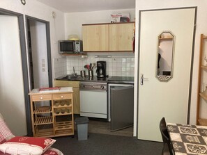 A compact kitchen with a microwave, stove, sink, and a small refrigerator. There is a wooden cabinet above the stove and a microwave on the wall. A trash bin is visible near the sink. - Apartment 4 guests, slope view - Le Pleynet (Le Pleynet)