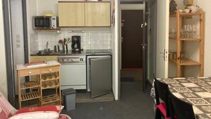A compact kitchen with a microwave, stove, and refrigerator. There is a small dining area with a table and chairs. - Apartment 4 guests, slope view - Le Pleynet (Le Pleynet)