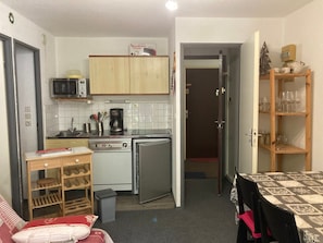 A compact kitchen with a microwave, stove, and refrigerator. There is a small dining area with a table and chairs. - Apartment 4 guests, slope view - Le Pleynet (Le Pleynet)