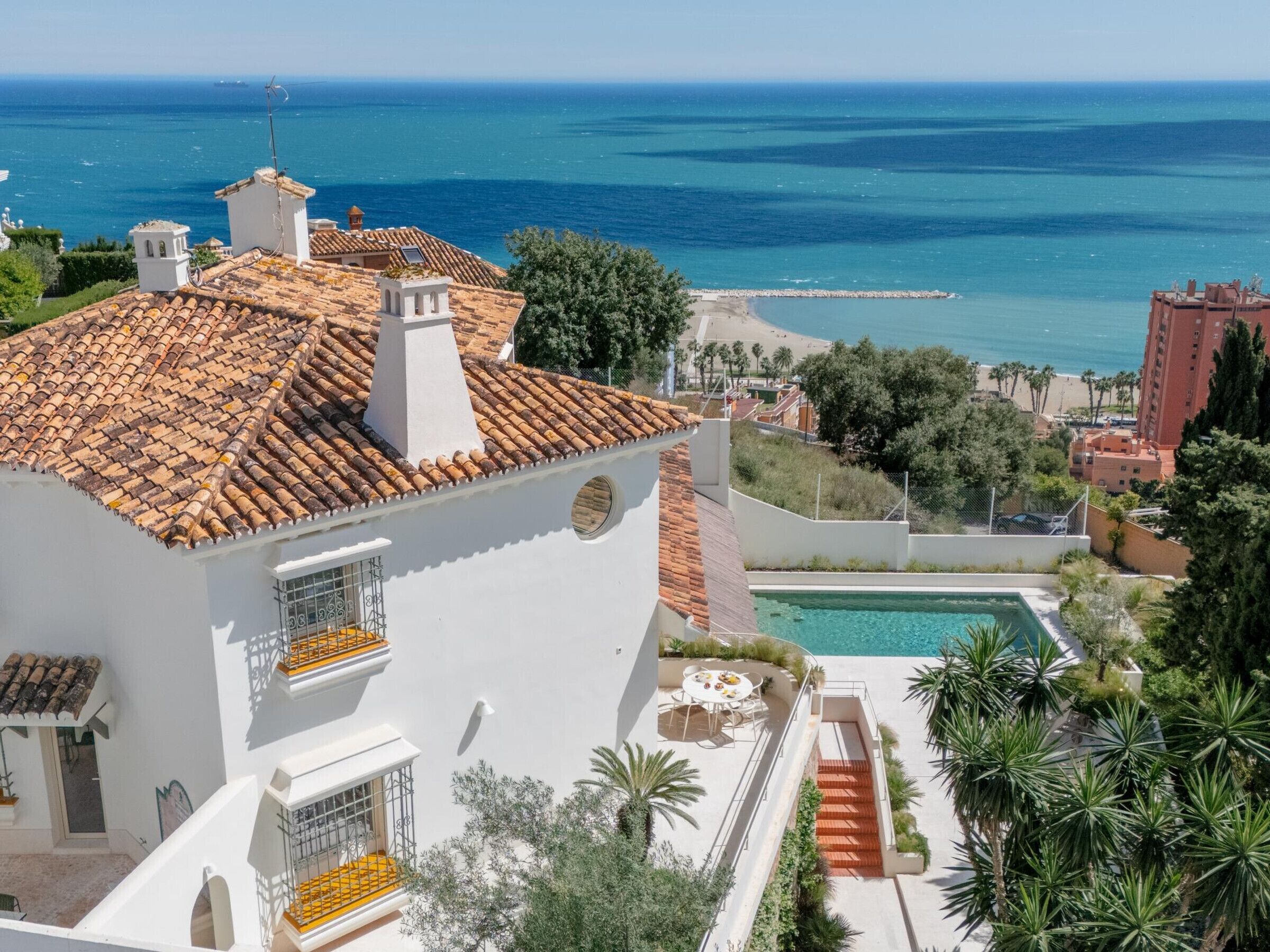 A coastal property with a swimming pool, a terrace, and a view of the sea.