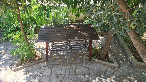 A wooden table with metal chairs in a garden setting.
