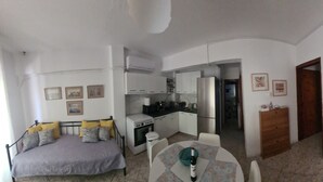 Ett kompakt bostadsutrymme med ett litet kök, en matplats och ett sovrum.