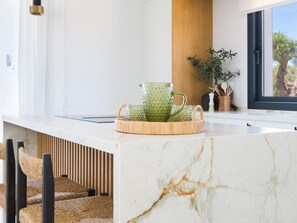 A kitchen with a marble countertop, wicker chairs, and a window with a view of trees. - Luxurious villa with private pool in Antequera (Antequera)