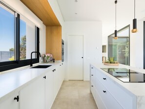 A modern kitchen with white cabinetry, a black faucet, and a wooden ceiling. - Luxurious villa with private pool in Antequera (Antequera)