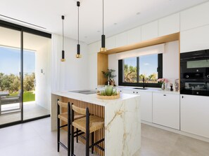 A modern kitchen with a central island, bar stools, pendant lighting, and a view of the outdoors. - Luxurious villa with private pool in Antequera (Antequera)