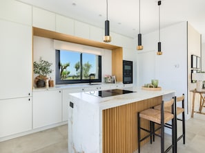 A modern kitchen with a large island, built-in appliances, and pendant lighting.