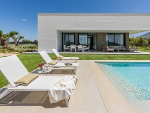 A modern outdoor pool area with lounge chairs and a dining set.