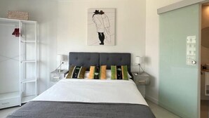A bedroom with a bed, bedside tables, a wardrobe, and a door. - Central apartment in Málaga - 2 guests (Málaga)