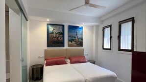 A double bed with a headboard, two wall-mounted paintings, a ceiling fan, and a window with blinds. - Central apartment in Málaga - 2 guests (Málaga)