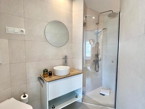 A modern bathroom with a round mirror, a sink, and a glass-enclosed shower. - Central apartment in Málaga - 2 guests (Málaga)