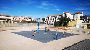 An outdoor exercise area with fitness equipment, surrounded by residential buildings. - Apartment with air conditioning, lake view - 4 guests (Le Barcarès)