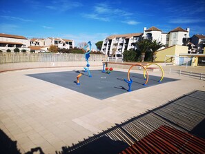 Ein Trainingsbereich im Freien mit Fitnessgeräten, umgeben von Wohnhäusern.