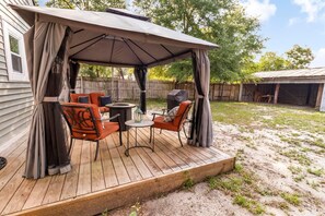 Eine Terrasse im Freien mit überdachter Sitzecke, einem Tisch und Stühlen.