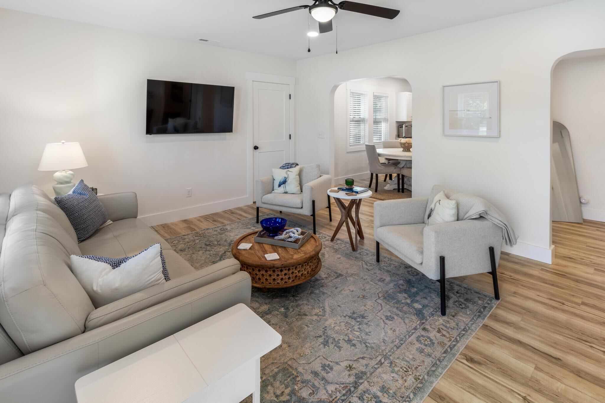 Una sala de estar moderna con un sofá, un sillón, una mesa de centro y un comedor con una mesa y sillas.