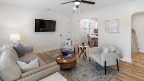 Un salon moderne comprenant un canapé, un fauteuil, une table basse et un coin repas avec une table et des chaises.