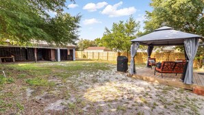 Un jardin avec un patio couvert, un barbecue et du mobilier d’extérieur.