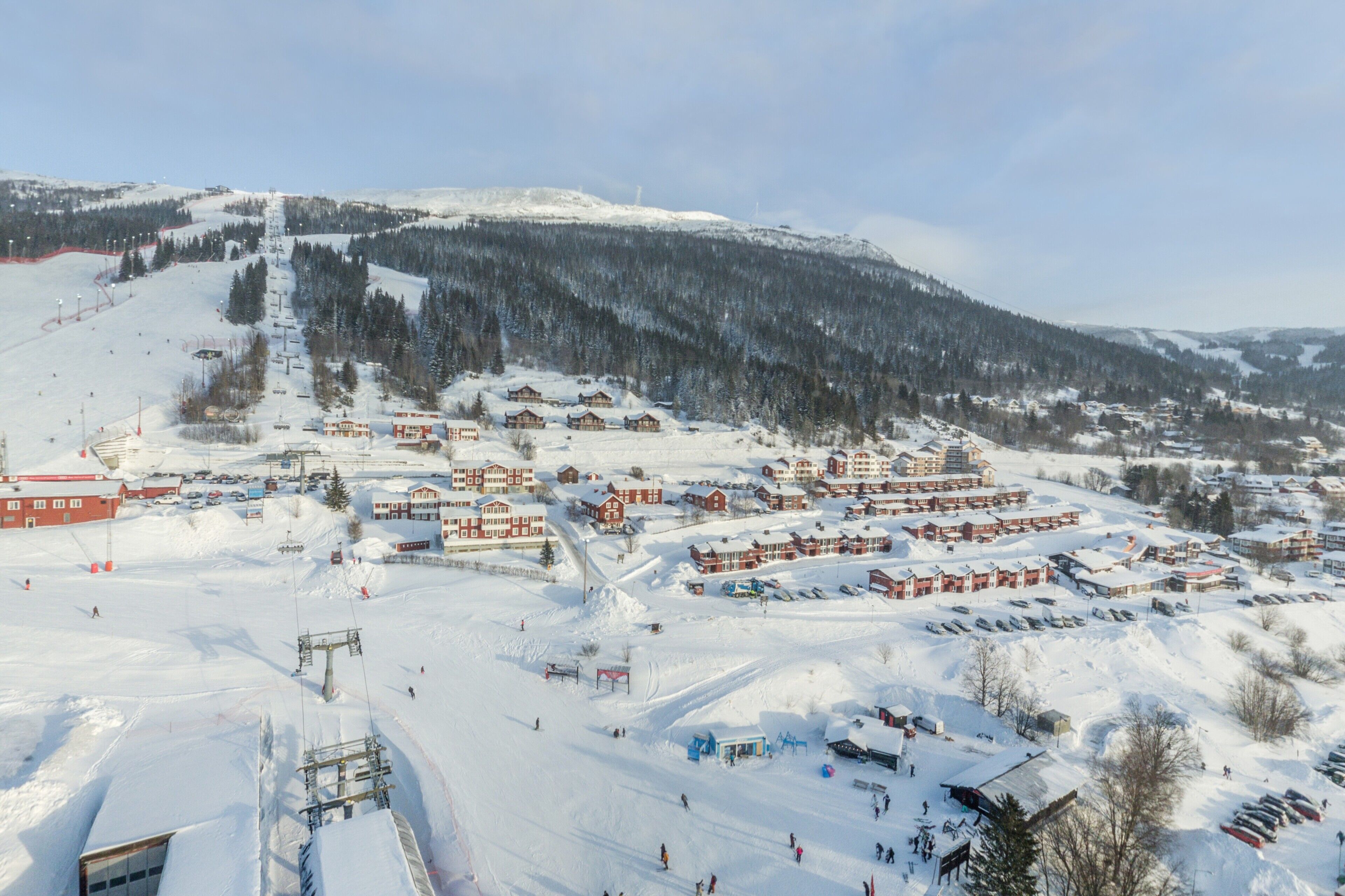 Un centro de esquí cubierto de nieve con varios edificios, telesillas y montañas al fondo.