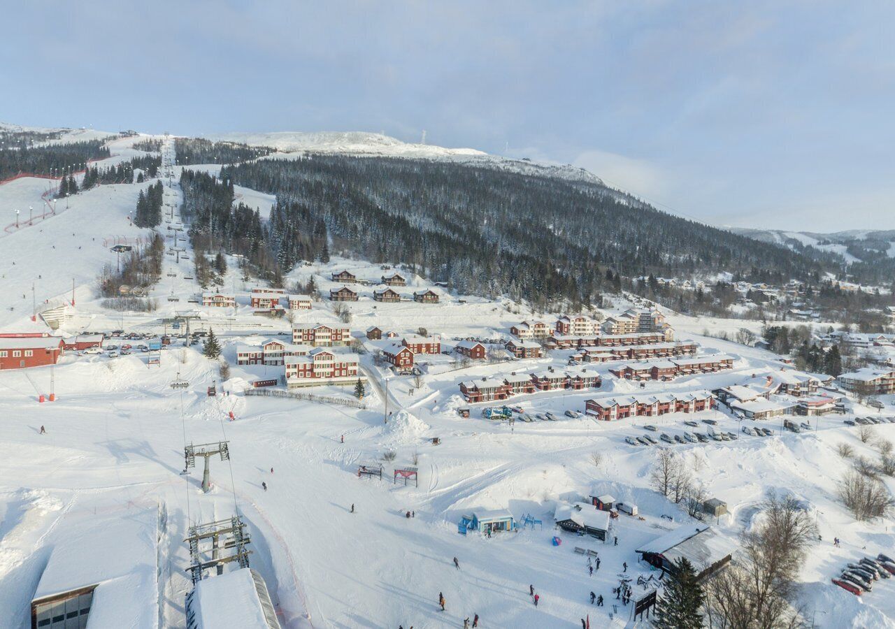 A snow-covered ski resort with multiple buildings, ski lifts, and a mountainous backdrop.