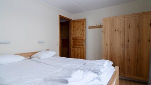 A bedroom with a double bed, wooden wardrobe, and a door leading to another room. - Åre Fjällby (Are)