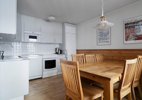 Una cucina moderna con mobili bianchi, un tavolo da pranzo in legno e sedie.
