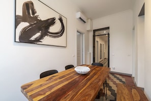 Ein moderner Essbereich mit einem Holztisch, Stühlen und einem großen abstrakten Gemälde an der Wand.