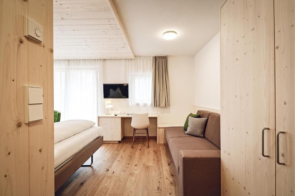 Une pièce de taille modeste comprenant un lit, un bureau, une chaise et un canapé.