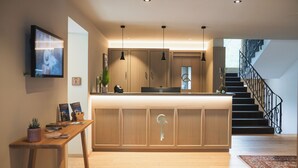 Una cocina moderna con una isla de madera, luces colgantes y una escalera que sube a un nivel superior.
