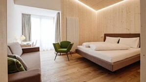 Habitación de hotel moderna con techo de madera, una cama, una silla verde y vistas al exterior.