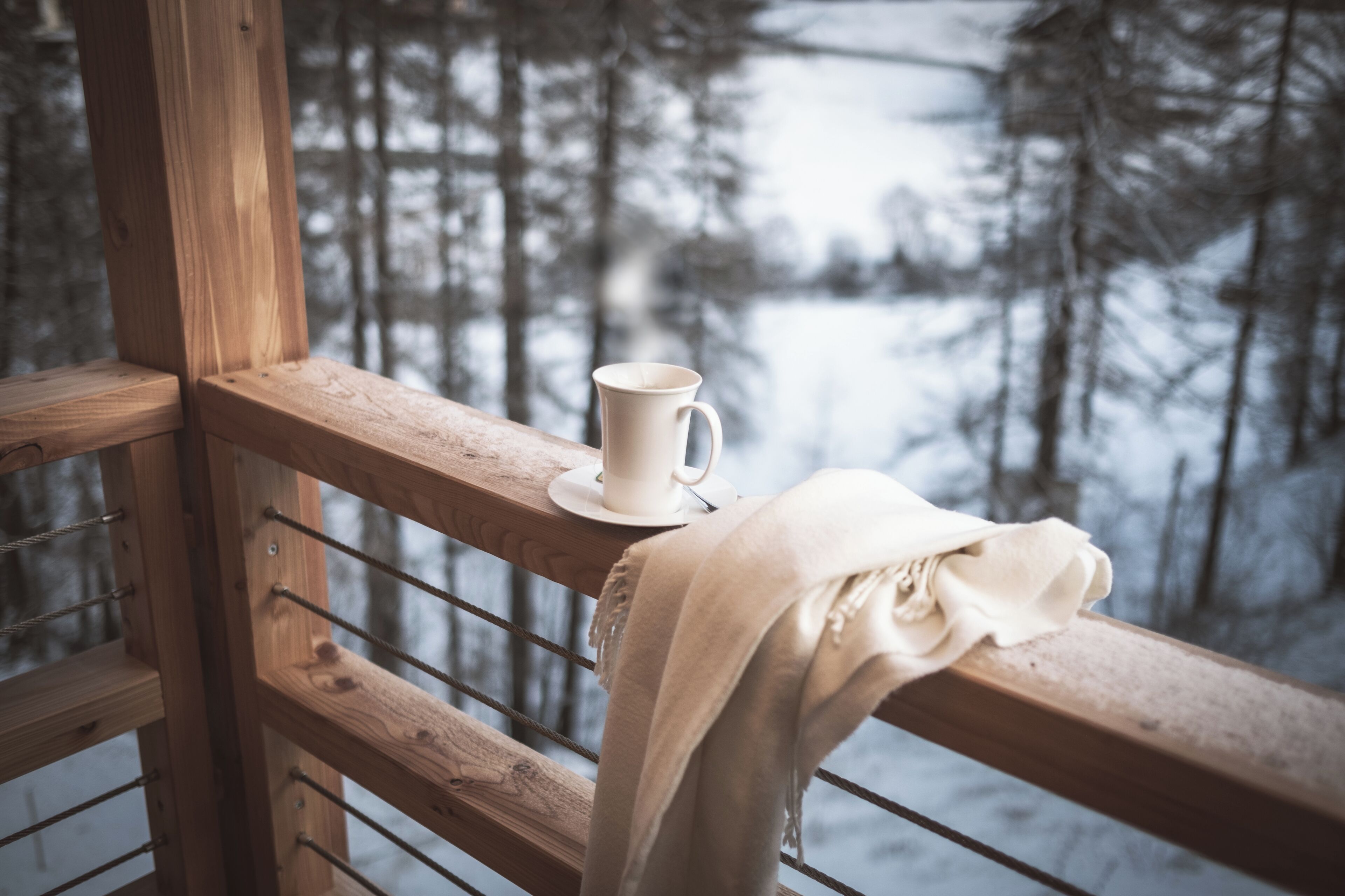 Un parapetto in legno con una tazza bianca su un piattino e un panno beige drappeggiato sopra.