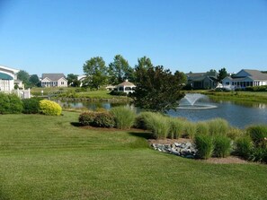 A residential area with a pond, a gazebo, and houses with a well-maintained lawn. - Pond Front Home with Magnificent Sunset views from the gorgeous Screened porch! (Lewes)
