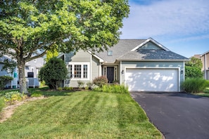 A residential house with a garage, a lawn, and a tree. - Pond Front Home with Magnificent Sunset views from the gorgeous Screened porch! (Lewes)