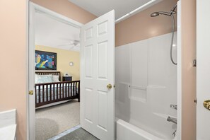 A bathroom with a shower, a door leading to a bedroom, and a wall with a clock. - Pond Front Home with Magnificent Sunset views from the gorgeous Screened porch! (Lewes)