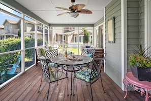 A covered patio with a table and chairs, a ceiling fan, and a view of neighboring houses. - Pond Front Home with Magnificent Sunset views from the gorgeous Screened porch! (Lewes)