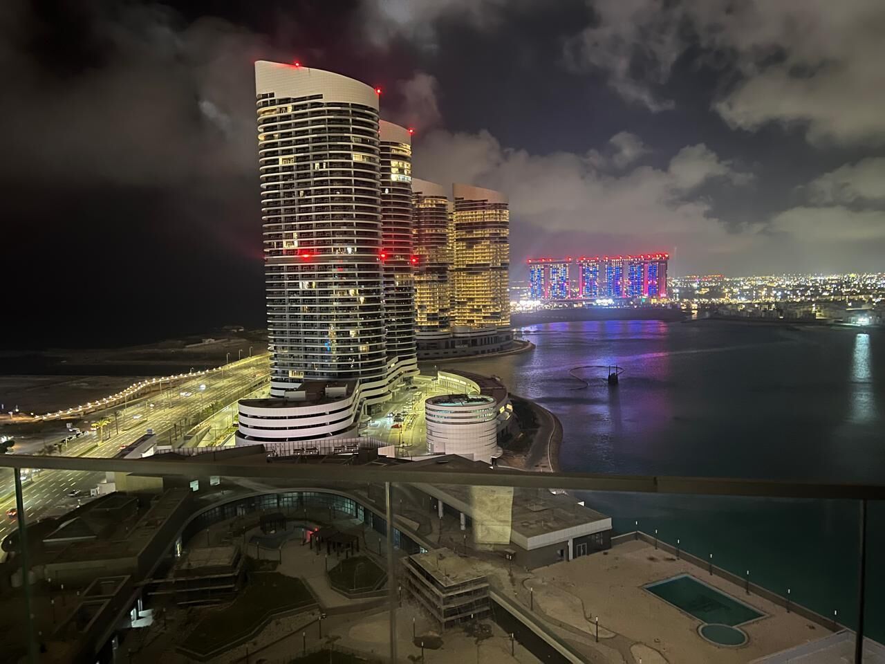 Um hotel moderno com fachada curva, situado perto da orla marítima, com vista para o horizonte da cidade.