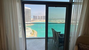 A balcony with a view of a beach and buildings. - Naya Suites; Luxury 2BR Panoramic Sea & Lagoon View, Beach Towers (Marsa Matrouh)