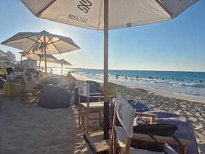 A beachside setting with umbrellas and lounge chairs, a clear view of the ocean, and a sandy beach. - Naya Suites; Luxury 2BR Panoramic Sea & Lagoon View, Beach Towers (Marsa Matrouh)