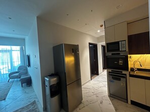 A modern kitchen with stainless steel appliances, a marble floor, and a view of the living area. - Naya Suites; Luxury 2BR Panoramic Sea & Lagoon View, Beach Towers (Marsa Matrouh)