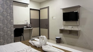 Habitació d'hotel amb llit, escriptori, cadira, televisió i ventilador de sostre.